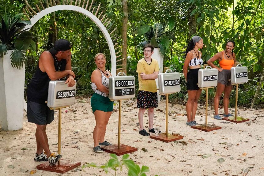 The cast stands next to their briefcases in Deal or No Deal Island Episode 110.