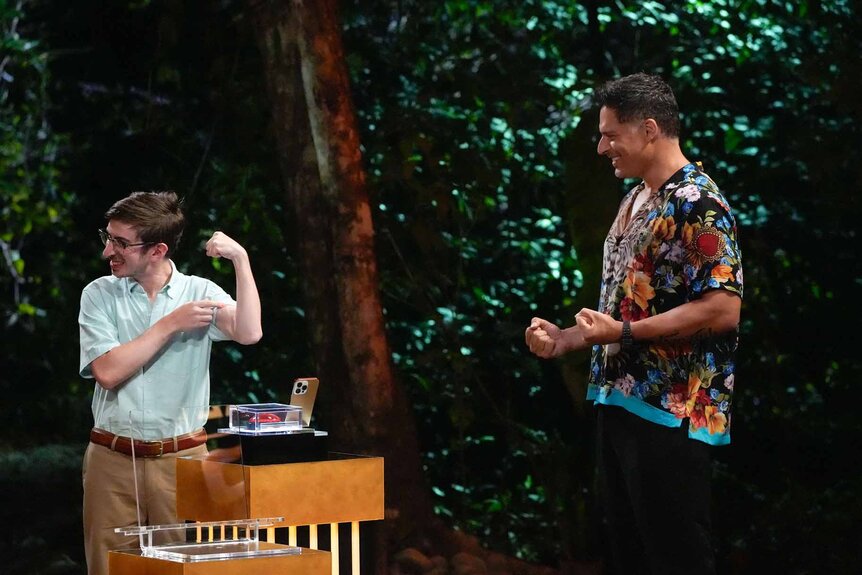 Aron Barbell flexes as Joe Manganiello smiles in Deal or No Deal Island Episode 110.