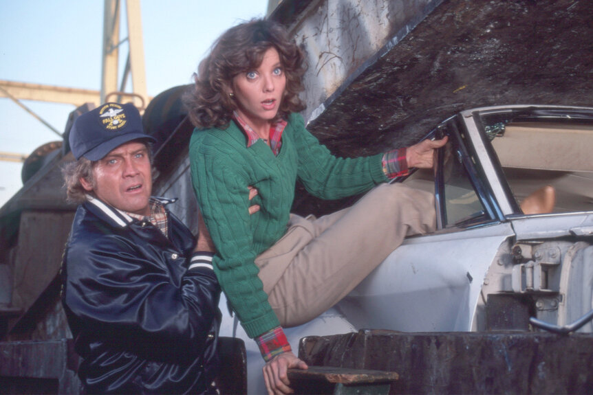 Lee Majors takes Judith Chapman out of a car on the fall guy