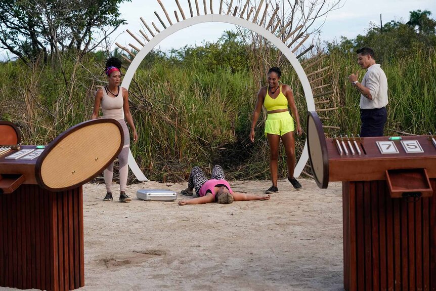 Stephanie Mitchell, Jordan Fowler, and Joe Manganiello watch as Amy McCoy flops on the sand on Deal or No Deal Episode 112.