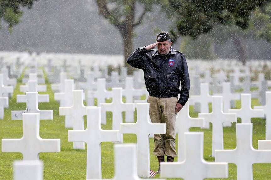 A man dressed with US military uniform pays tribute to a soldier during commemorations marking the 73th anniversary of D-Day