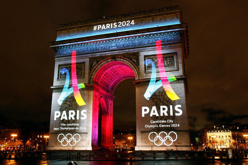 The Paris Olympics 2024 logos are projected onto the Arc de Triomphe.