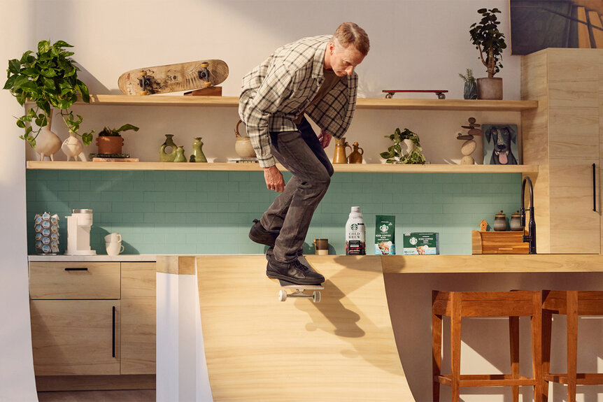 Tony Hawk skateboards down a ramp in a kitchen for a collab with starbucks