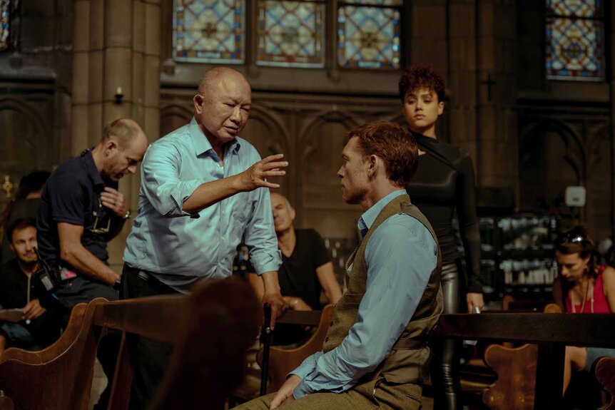 Director John Woo, Sam Worthington and Nathalie Emmanuel speak on the set of The Killer (2024).