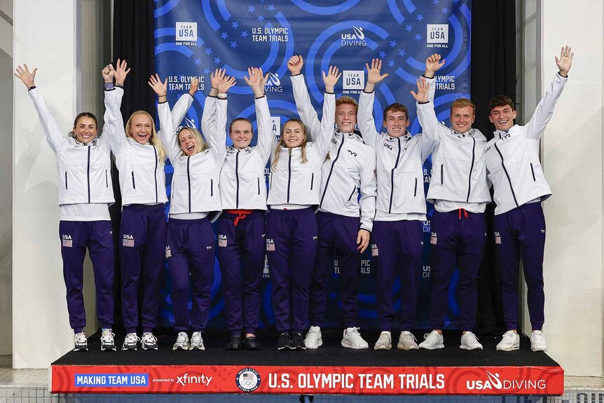 The 2024 US Olympic Dive Team pose for a portrait with their hands up.