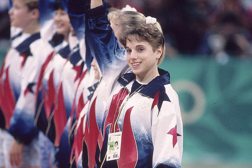 Kerry Kerri Strug waving and smiling with teammates during Team All-Around at the Georgia Dome.