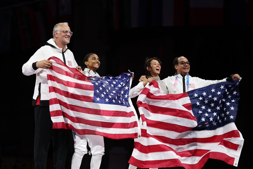 Lee Kiefer and Lauren Scruggs hold up the american flag at the Paris Olympics