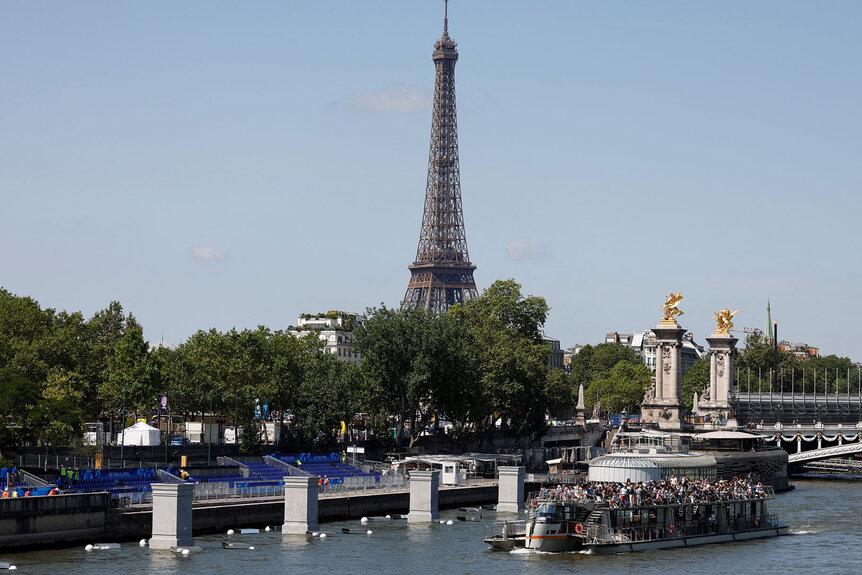 A tourist boat passes next to Paris 2024 opening ceremony structures and the Eiffel Tower