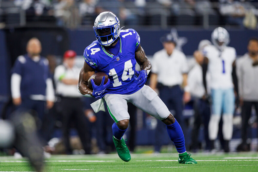 Dk Metcalf runs with the ball on the field during a NFL game