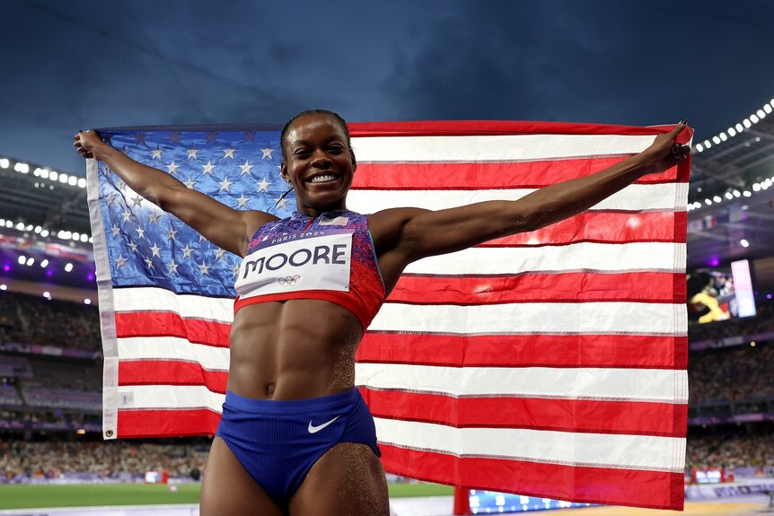 Jasmine Moore holds an American flag after winning a bronze medal at the 2024 Olympics