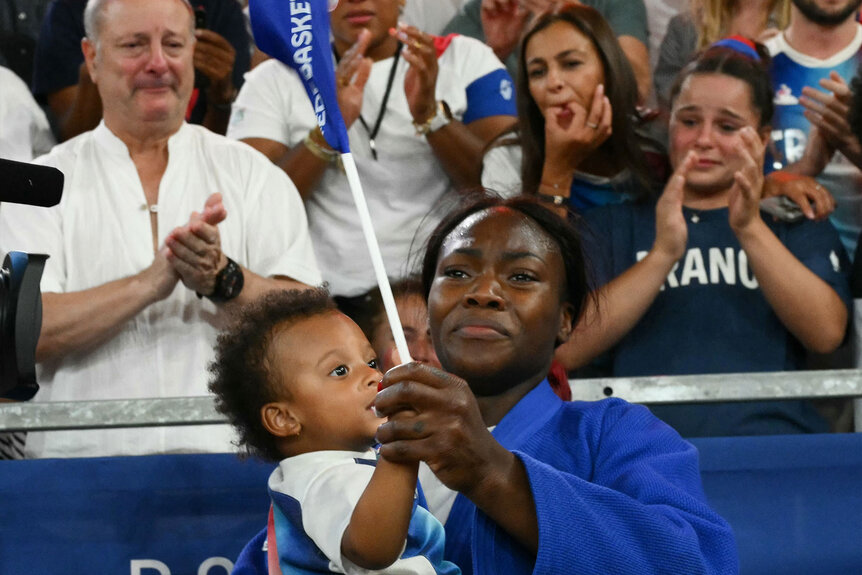 France's Clarisse Agbegnenou holds her baby as she reacts after beating Austria's Lubjana Piovesana in the judo women's -63kg bronze medal bout of the Paris 2024 Olympic Games