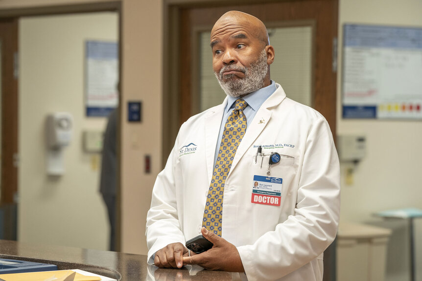 Dr. Ron reacting and standing behind a desk.