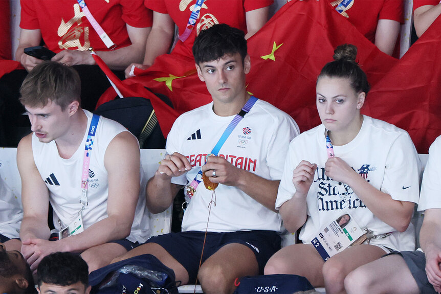 Tom Daley knits as he sits in the stands at the 2024 olympics