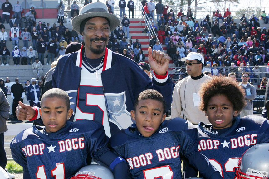 Snoop Dogg poses with three young football players during the "Snooper Bowl"