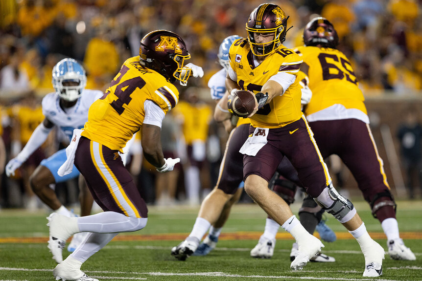 Minnesota Golden Gophers quarterback Max Brosmer hands the ball off to running back Marcus Major