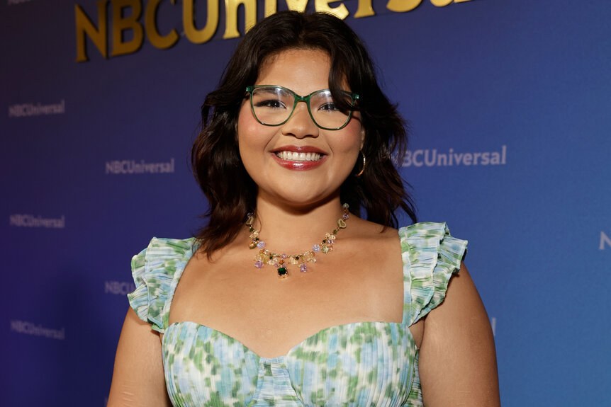 Belissa Escobedo wears a floral dress and smiles on the red carpet