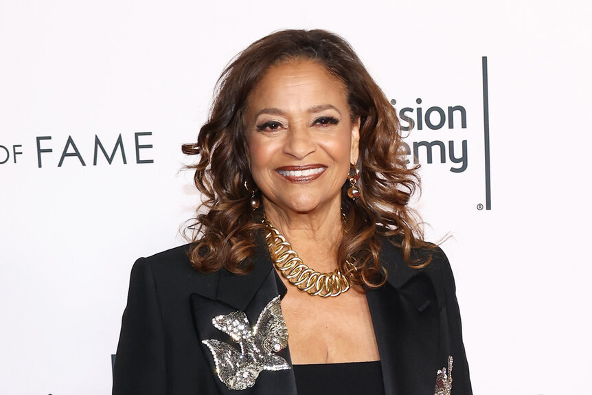 Debbie Allen smiles in a black outfit.