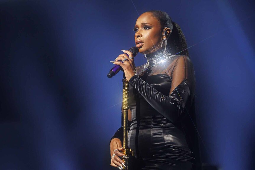 Jennifer Hudson sings onstage in a black gown.