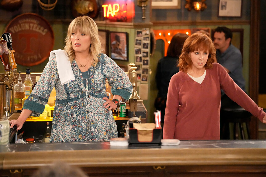 Gabby (Melissa Peterman) and Bobbie (Reba McEntire) stand behind a bar together in Happy's Place Season 1, Episode 1.