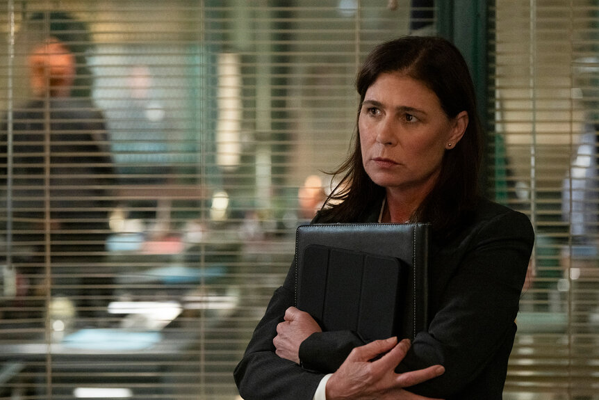 Jessica Brady holds an ipad and book close to her chest on Law and Order Season 24 Episode 3