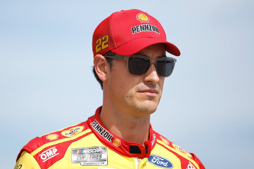 Joey Logano wears sunglasses and a red hat during qualifying for the NASCAR Cup Series Hollywood Casino 400