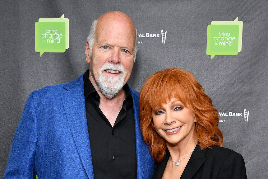 Rex Linn wears a blue jacket with Reba McEntire on the red carpet for an event