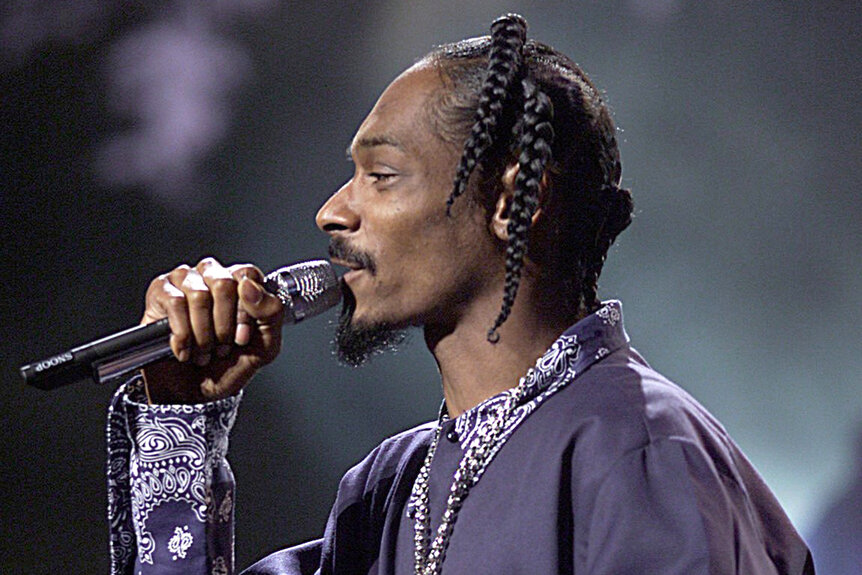 Snoop Dogg wears a purple jacket while performing on stage