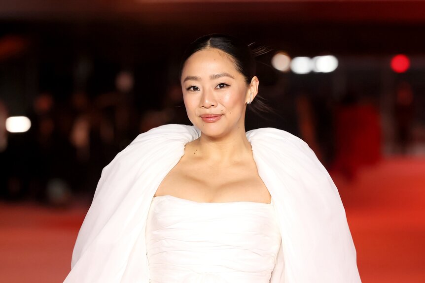 Stephanie Hsu smiles in a white gown.