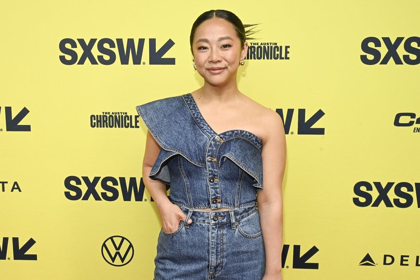 Stephanie Hsu smiles in a denim dress.