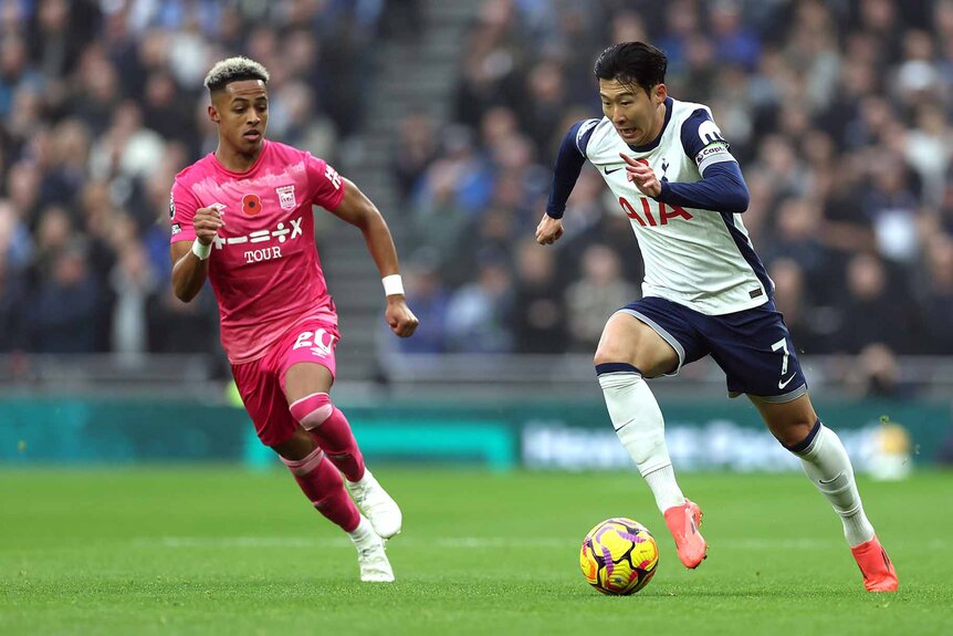 Ipswich Town's Omari Hutchinson and Tottenham Hotspur's Son Heung-Min chase after the ball during a game.