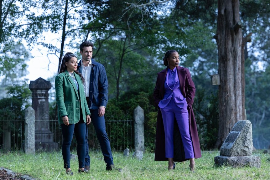 Lacey (Gabrielle Walsh), Detective Mark Trent (Brett Dalton), and Gabi (Shanola Hampton) stand in a cemetery on Found Episode 208.