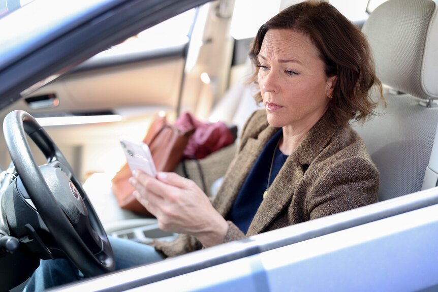 Margaret (Kelli Williams) looks at her phone in a car on Found Episode 208.