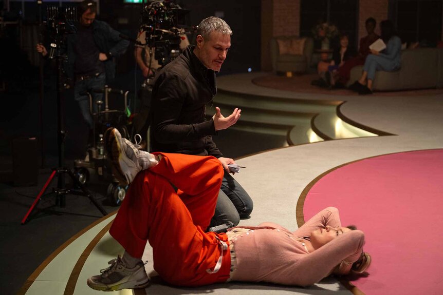 Director Michael Morris talks to a laying Bridget Jones (Renée Zellweger) on the set of Bridget Jones: Mad About the Boy (2025).