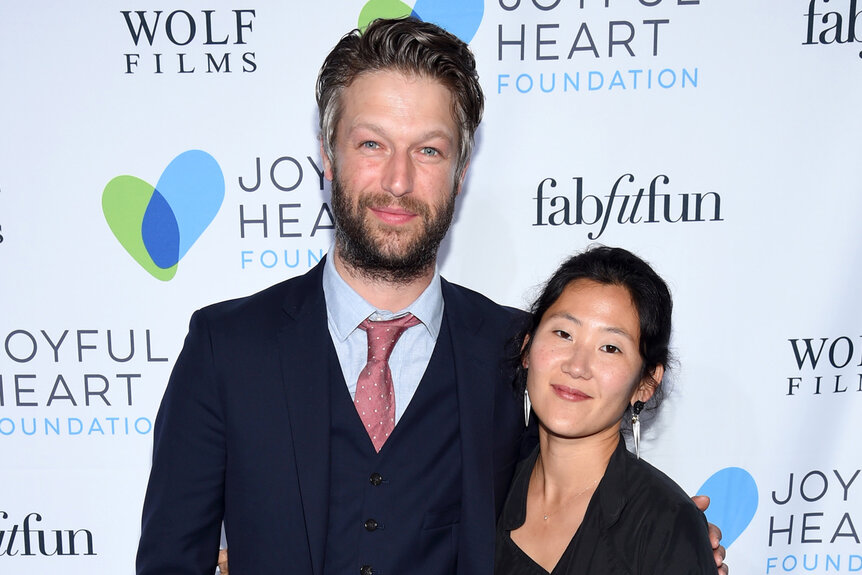 Peter Scanavino and Lisha Bai embrace each other while posing on the red carpet