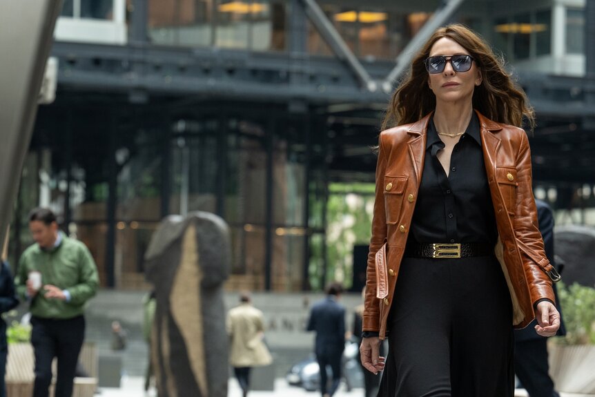 Kathryn St. Jean (Cate Blanchett) struts in a brown coat and sunglasses in Black Bag (2025).