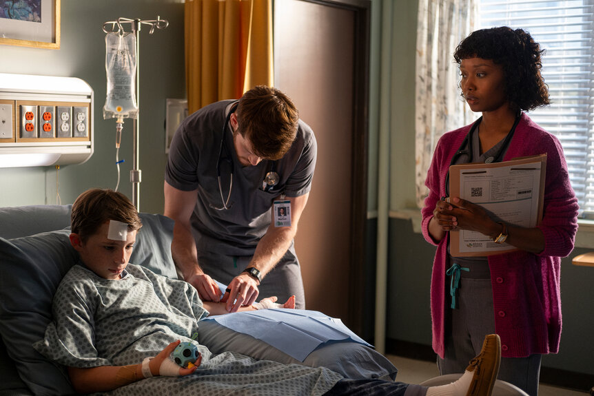 Finn Kemp sits in a hospital bed while Dr Van Markus and Ericka Kinney stand near him on Brilliant Minds Season 1 Episode 10