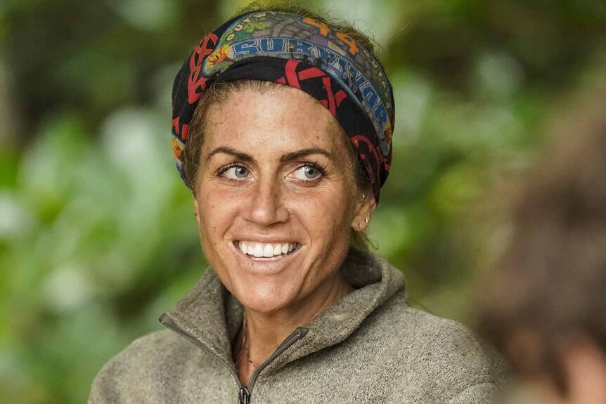 Carolyn Wiger smiles in a sweater and multi-colored headband.