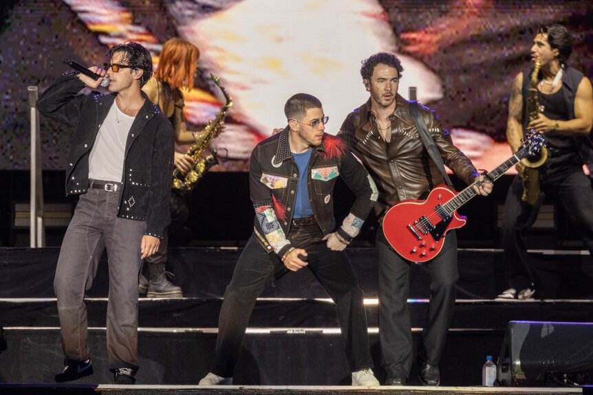 Joe Jonas, Nick Jonas and Kevin Jonas of Jonas Brothers perform onstage in black outfits.