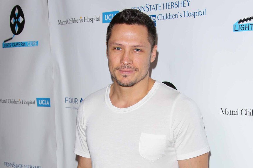 Nick Wechsler wears a white t-shirt.