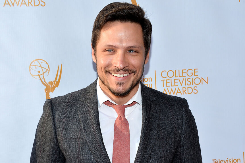 Nick Wechsler smiles in a grey suit and salmon tie.