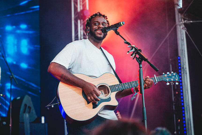 Myles Smith smiling and performing on stage.