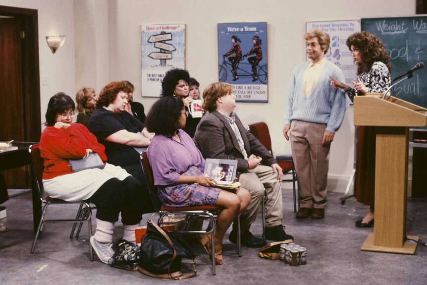 Amanda (Delta Burke), Ned Crowley (Chris Farley), Stuart Smalley (Al Franken), and Val (Julia Sweeney) sit in a classroom during an SNL sketch.