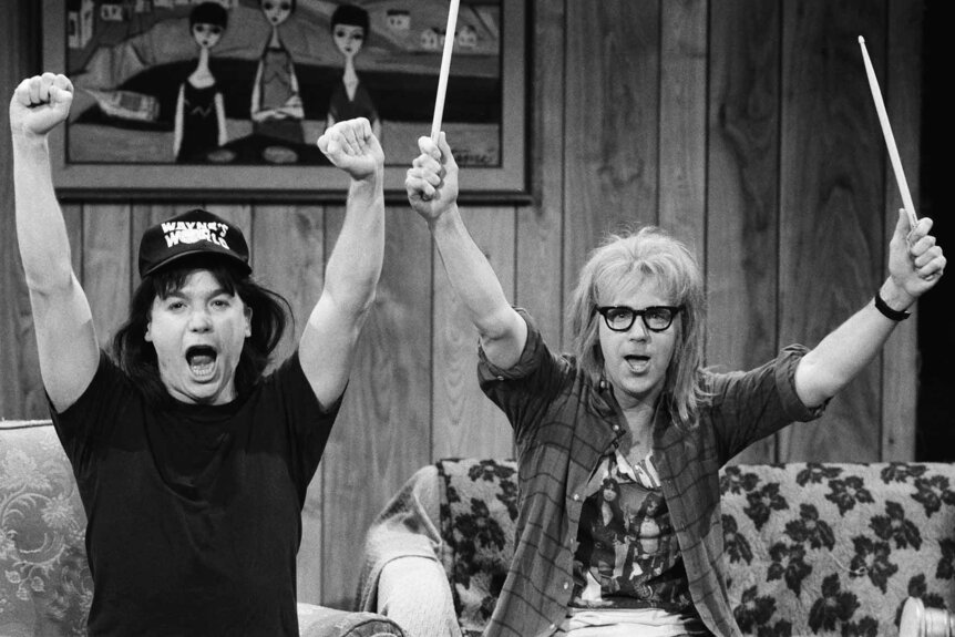 Wayne Campbell (Mike Myers) and Garth Algar (Dana Carvey) raise up their arms in cheer during an SNL sketch.