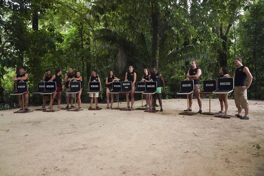 The cast stands with open briefcases on Deal or No Deal Island Episode 201.