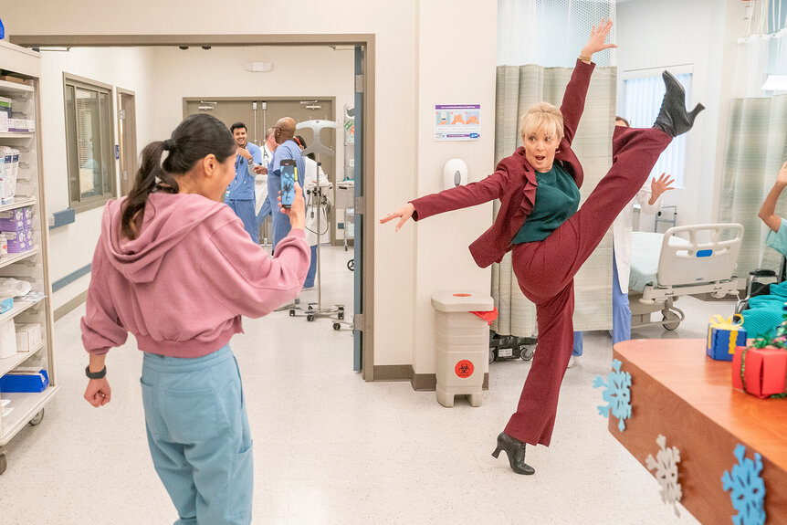 Serena films Joyce as she kicks her leg on St. Denis Medical Season 1 Episode 6.