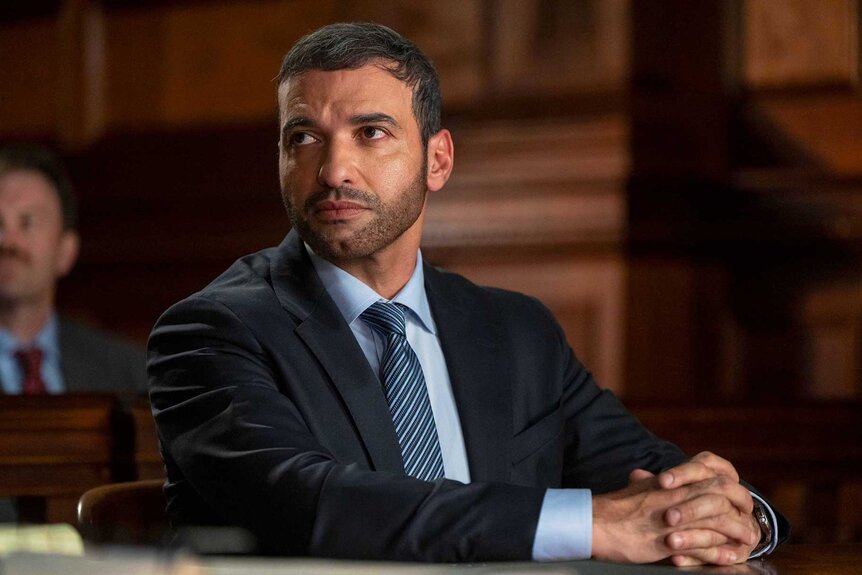 Joshua Haddad sitting with his hands folded on Law & Order Season 24 Episode 9.