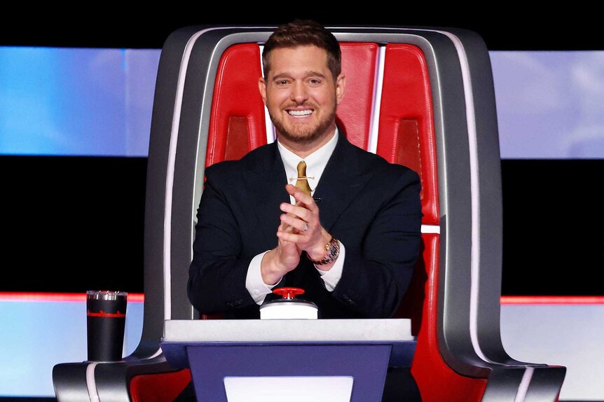 Michael Bublé clapping and smiling in the coaches chair on The Voice Season 27, Episode 1.