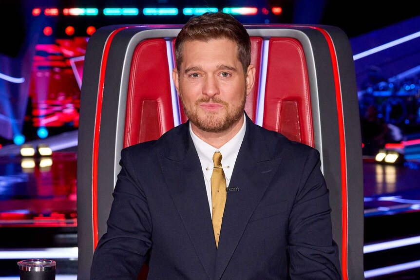 Michael Bublé smiling in the coaches chair on The Voice Season 27, Episode 1.