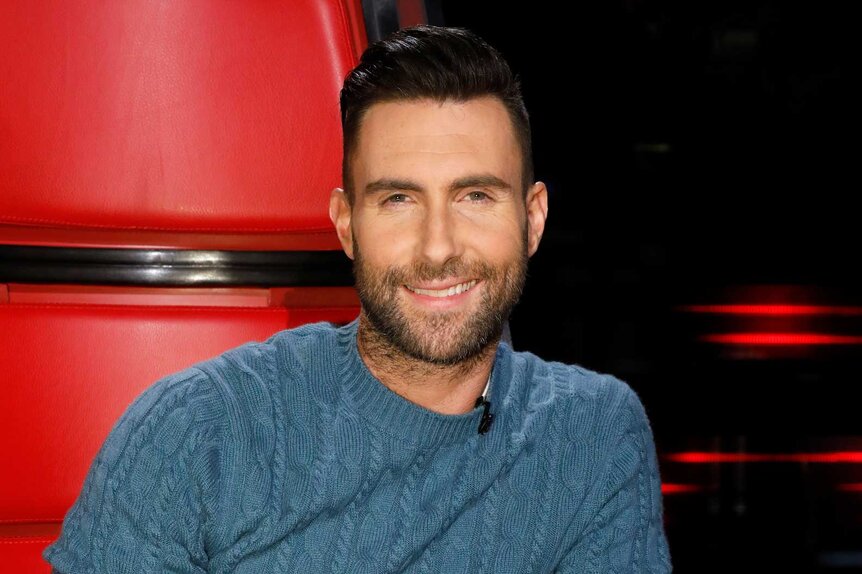 Adam Levine smiles in a blue sweater on The Voice Season 11, Episode 15A.