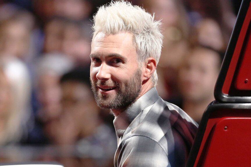 Adam Levine turns in his chair with blonde hair on The Voice Season 12, Episode 16B.